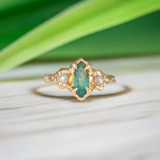 Emerald and diamond engagement ring, featuring a marquise cut emerald and salt & pepper diamonds in 14k gold.