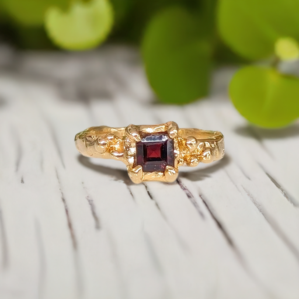 Handcrafted red garnet engagement ring in solid 14k gold with organic textured band.