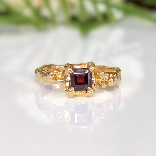 Solid 14k Gold engagement ring featuring square cut Red Garnet, showcasing organic textured band and timeless elegance.