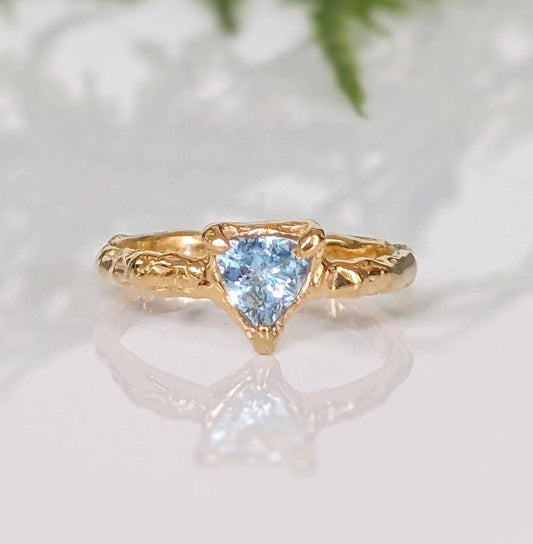 Solid Gold Aquamarine ring with textured band, featuring a unique triangular blue crystal centerpiece.