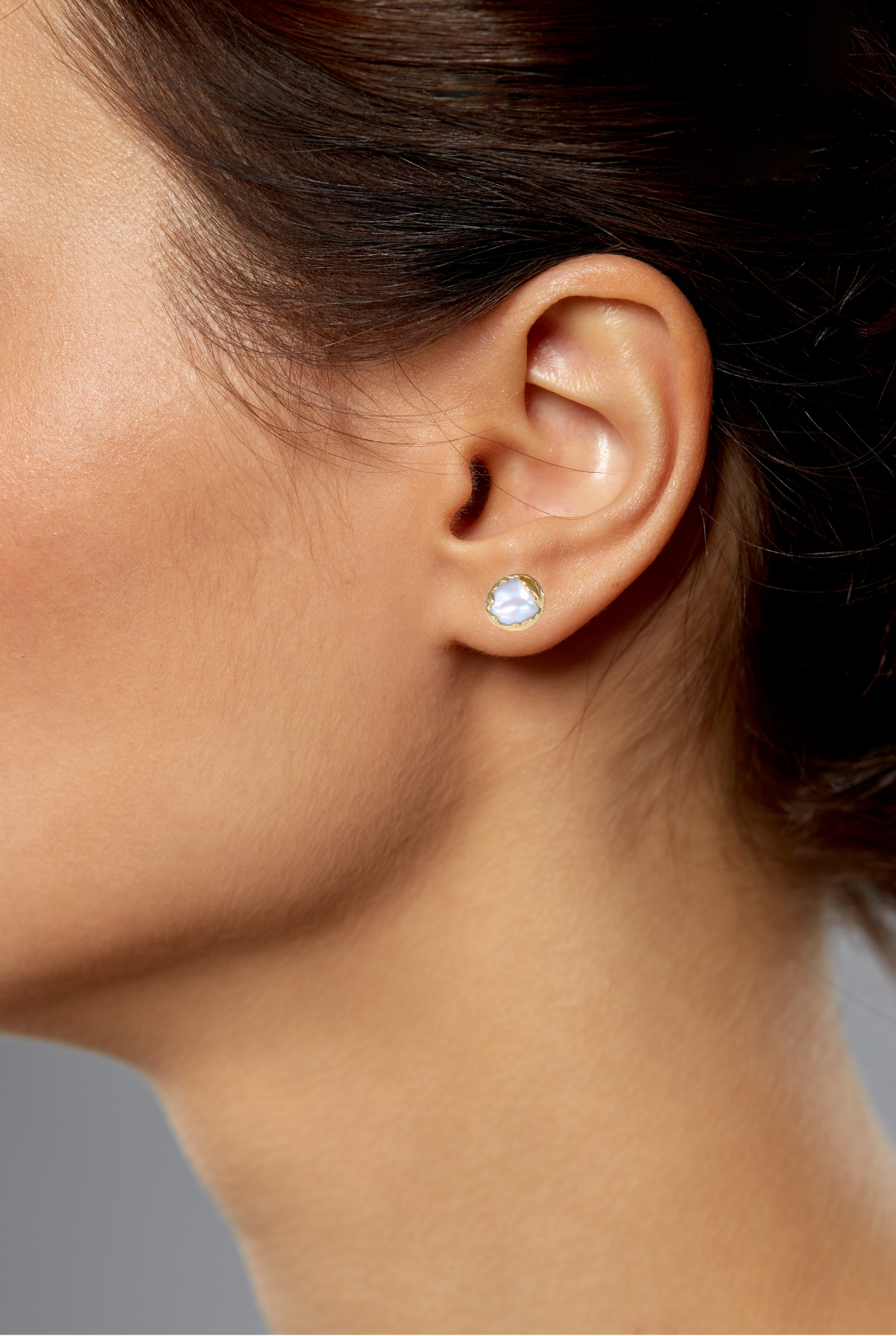 Close-up of a model's ear wearing Pea in a Pod freshwater pearl stud earrings, showcasing their elegant design.