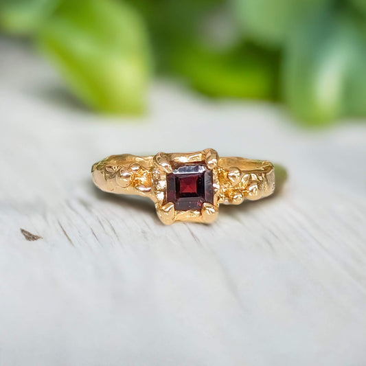 Handcrafted red garnet engagement ring in solid 14k gold with an organic textured band.
