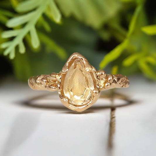 Handcrafted solid 14k gold citrine ring featuring a pear-shaped yellow crystal and textured organic band.