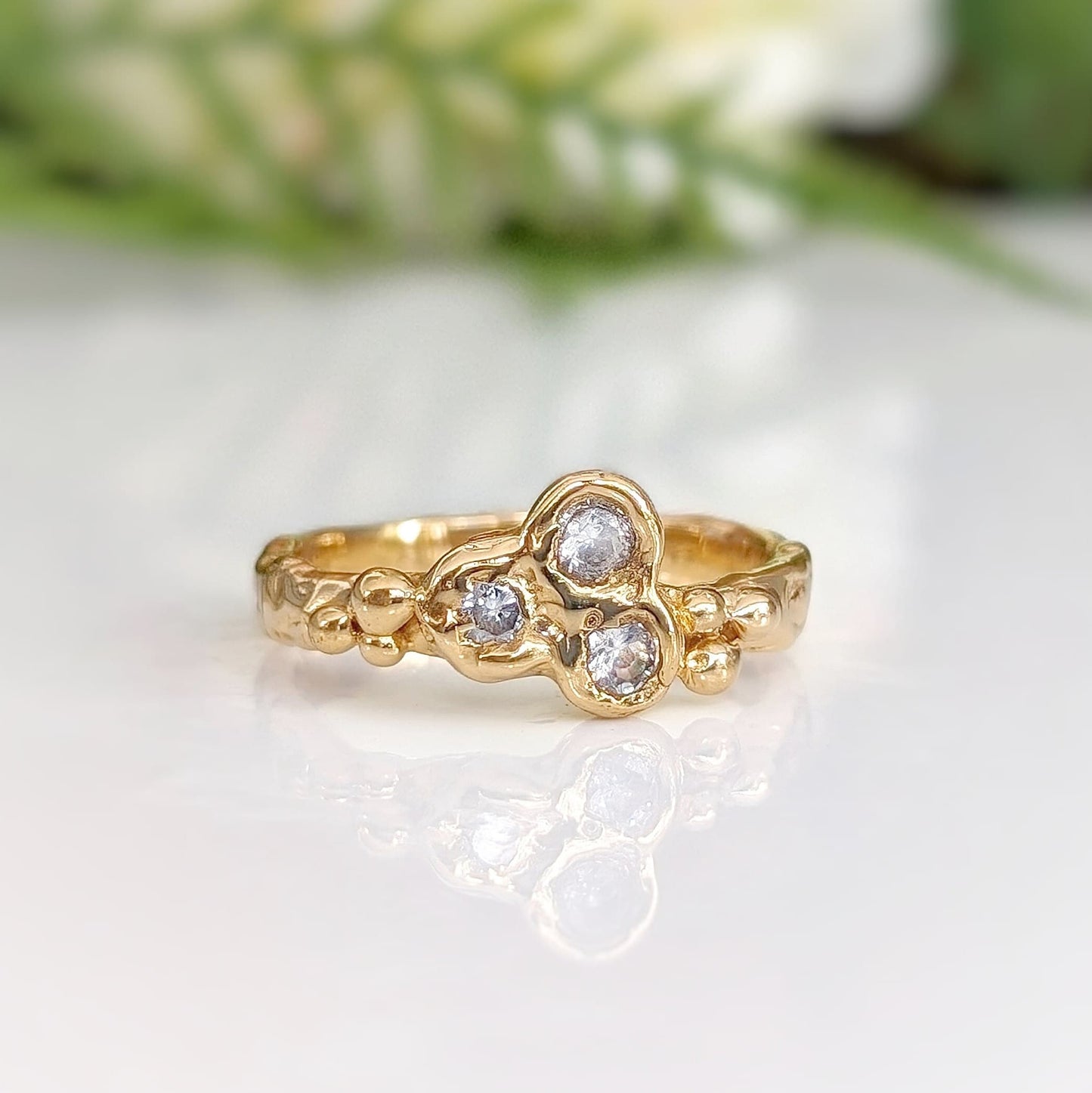 Gold cubic zirconia cluster ring with organic molten band, showcasing a unique and elegant design.