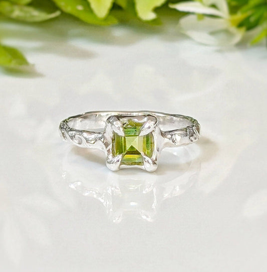Handcrafted solid silver Peridot ring with a princess-cut stone on an organic textured band.