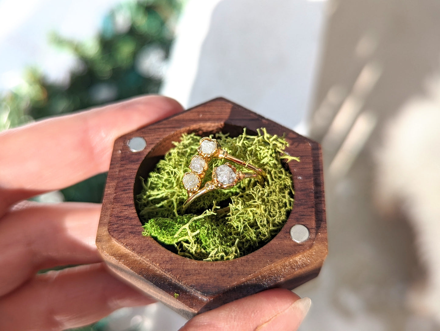 Handmade raw diamond wedding ring set displayed in a wooden hexagon box with moss.