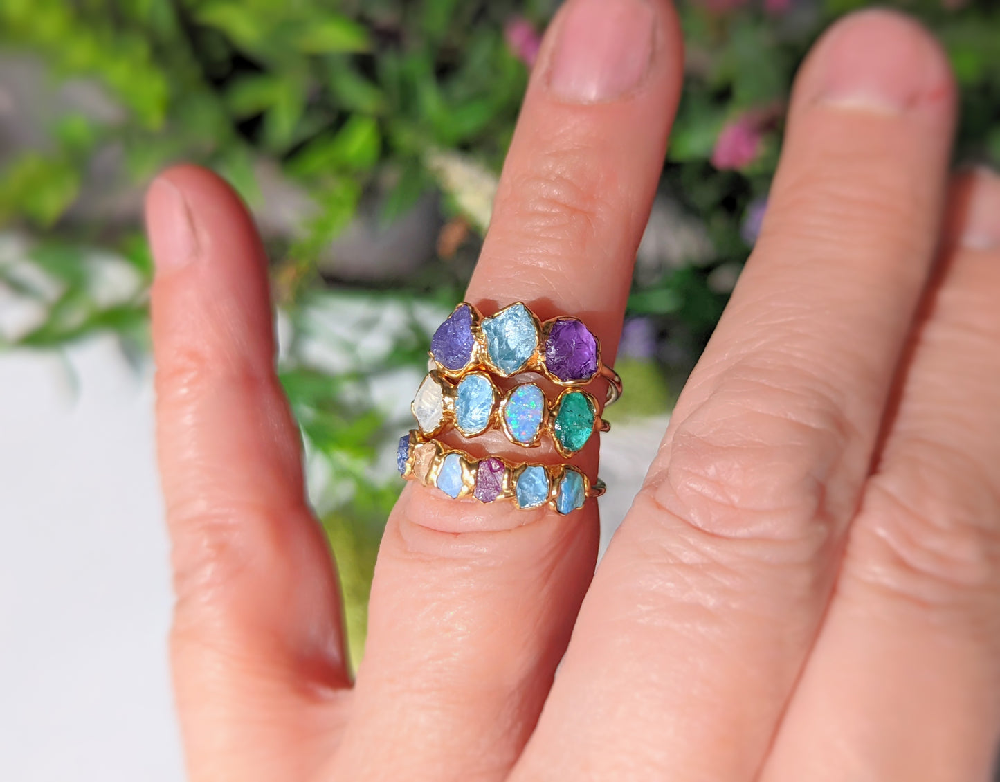 Three layered raw gemstone rings featuring colorful birthstones on a hand, perfect for a unique Mother's ring.