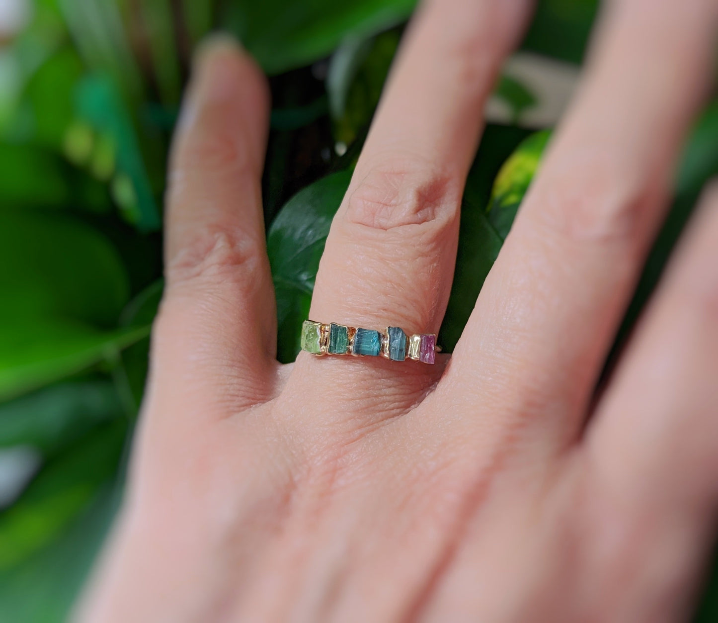 Colorful multi Tourmaline eternity ring worn on a hand, featuring five raw stones set on a delicate band.