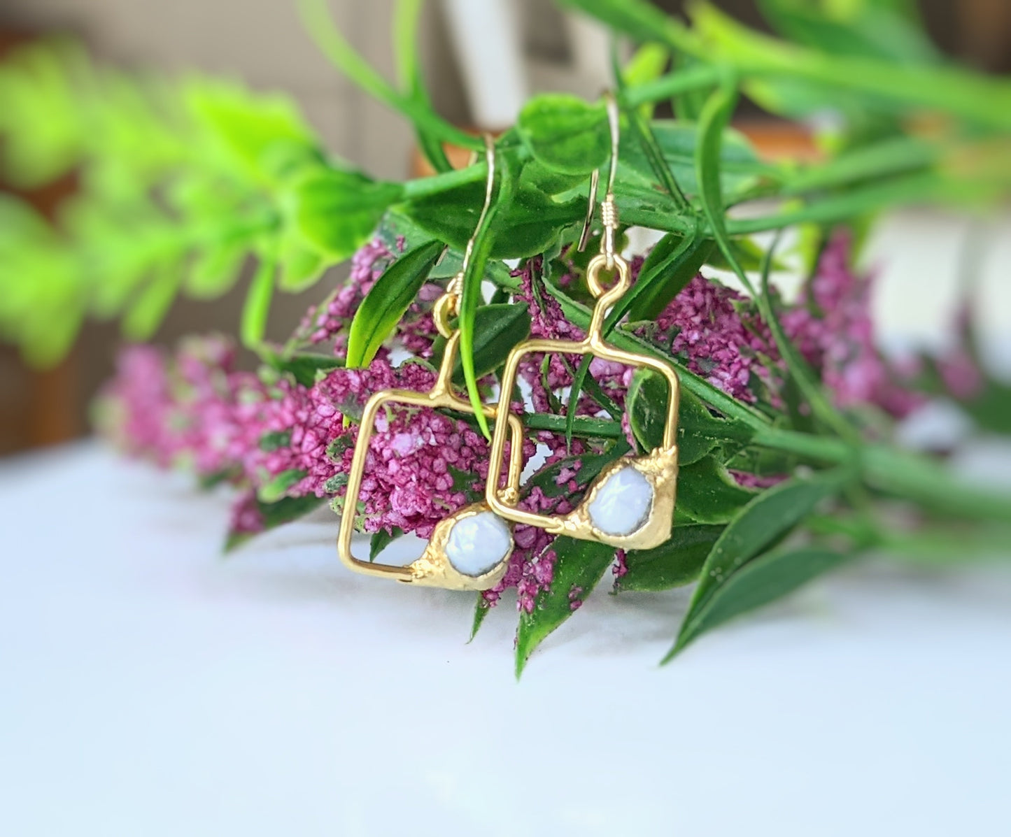 Keshi pearl square dangle earrings with gold setting and floral background.