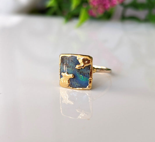 Australian Opal Kintsugi ring with gold accents on a reflective surface, showcasing unique design and craftsmanship.