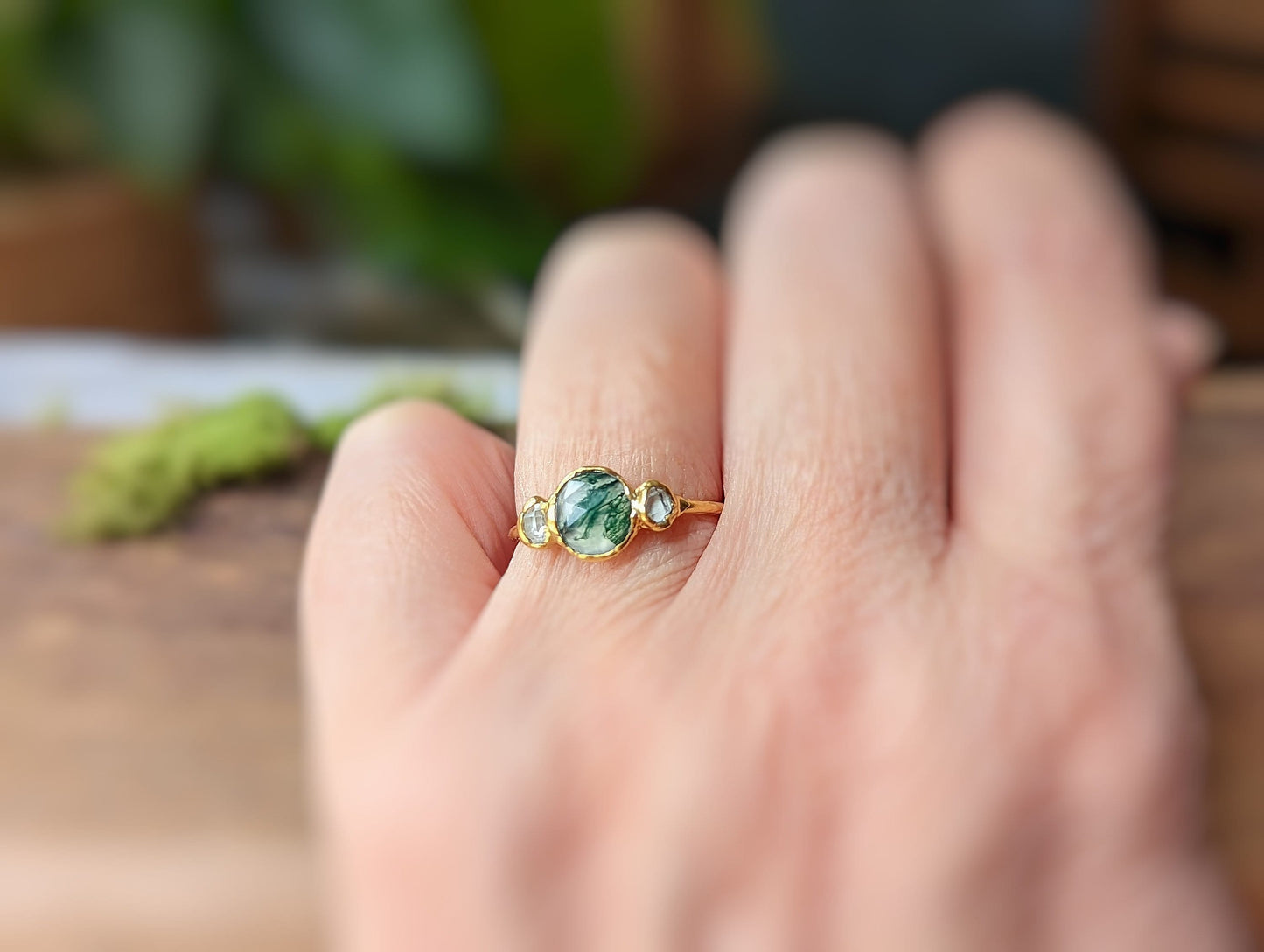 Moss Agate and Herkimer diamond engagement ring on a hand, showcasing unique rustic elegance.