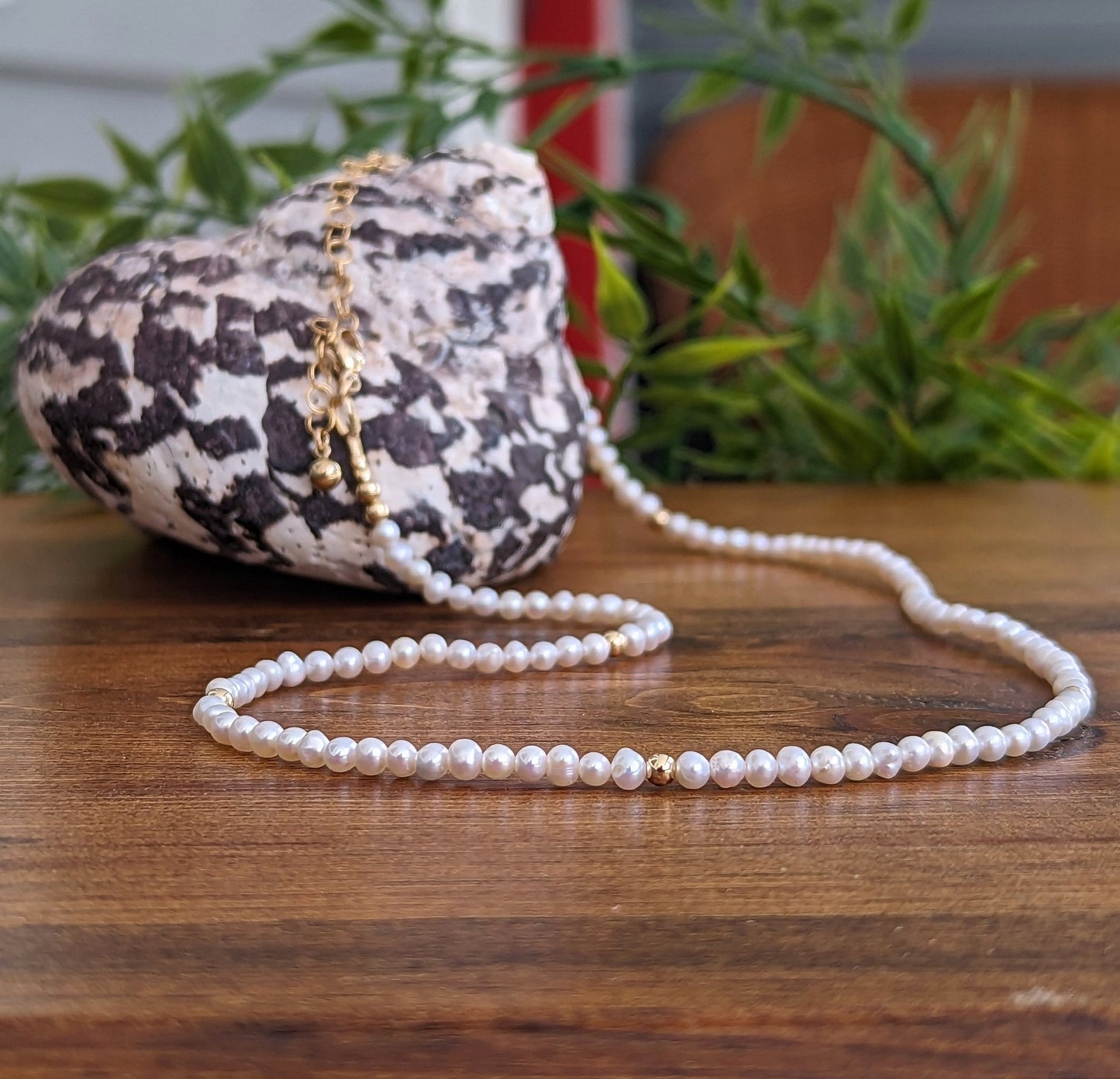Freshwater pearl necklace displayed on wooden surface with seashell backdrop, perfect for weddings or Mother's Day gifts.