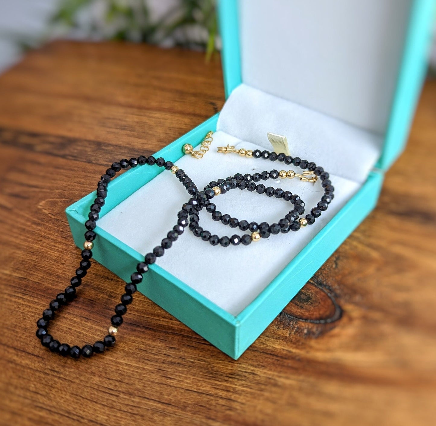 Elegant black spinel bead necklace displayed in a teal jewelry box, perfect for gifts and special occasions.
