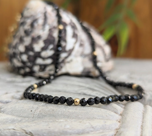 Elegant black spinel bead necklace with shimmering beads and gold accents, perfect for any occasion.