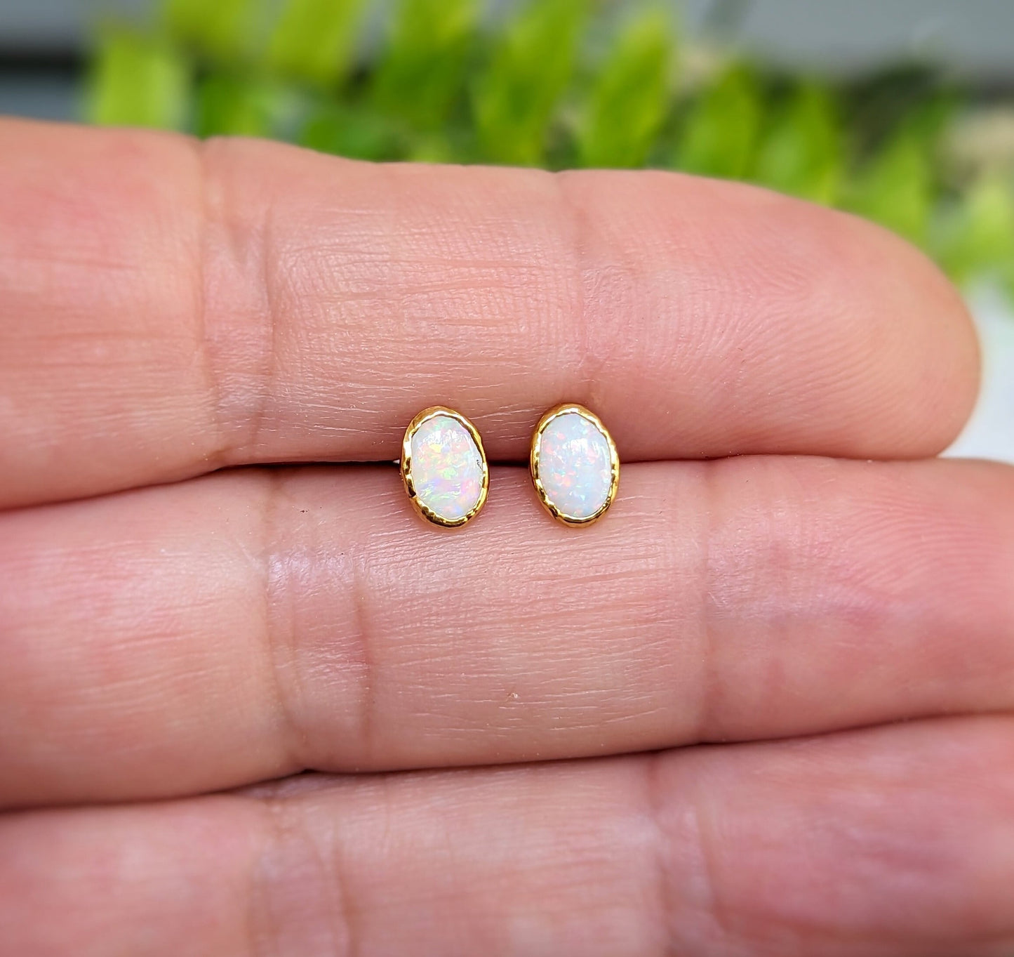 Handcrafted white Australian Opal stud earrings on a hand, featuring 14k Gold filled posts and 18k Gold plating.