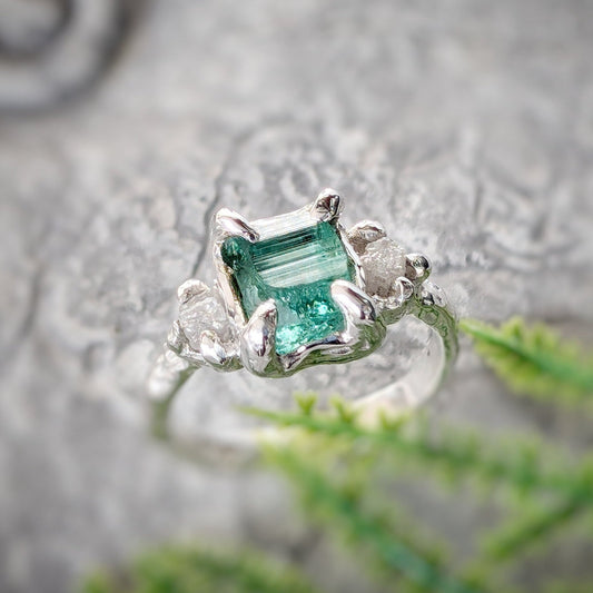 Raw emerald and diamond engagement ring in solid sterling silver with a mint green emerald and conflict-free diamonds.