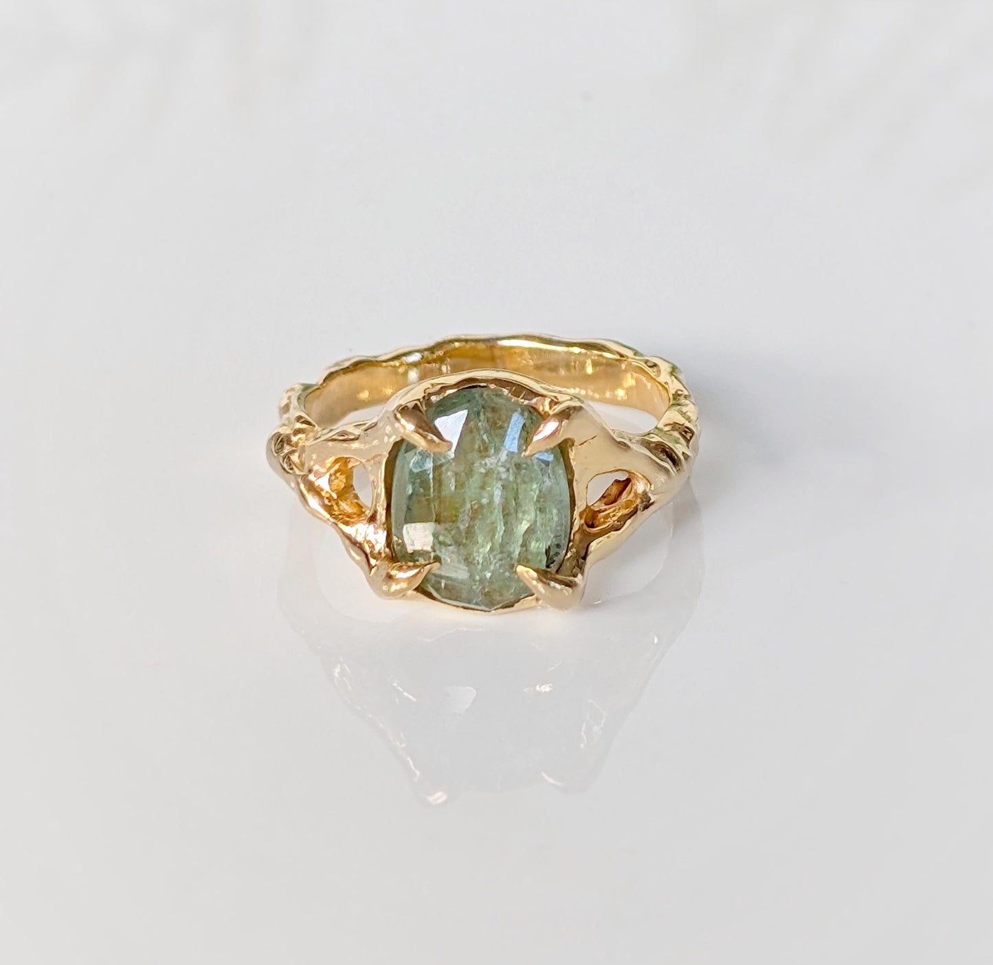 Solid gold textured ring featuring an oval rose cut green kyanite stone, showcasing unique handcrafted artistry.