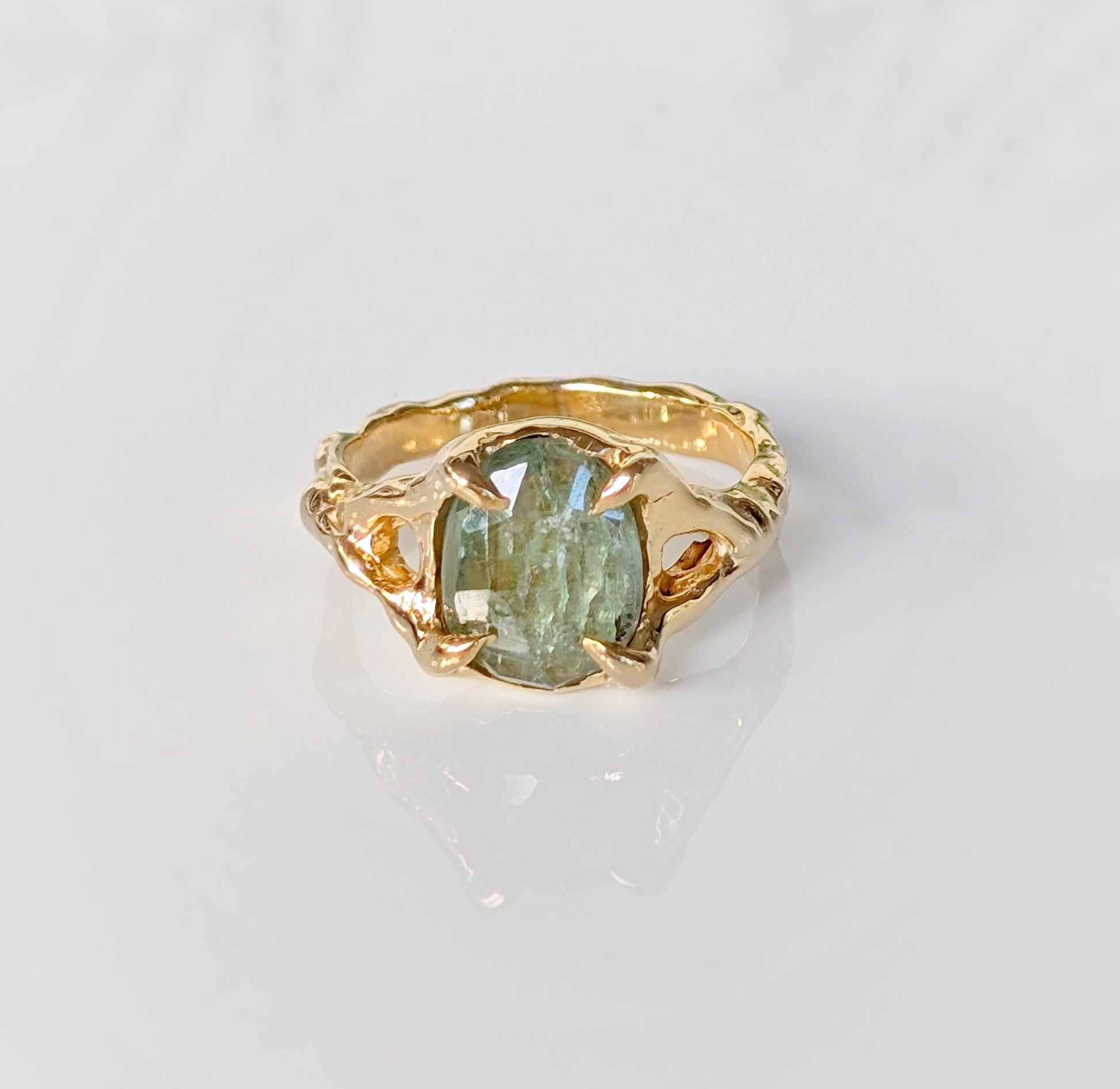 Solid gold textured ring featuring an oval rose cut green kyanite stone, showcasing unique handcrafted artistry.