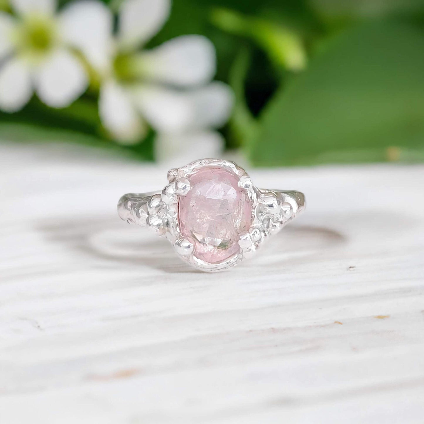 Handcrafted pink Morganite ring set in silver with floral background, showcasing elegance and charm.