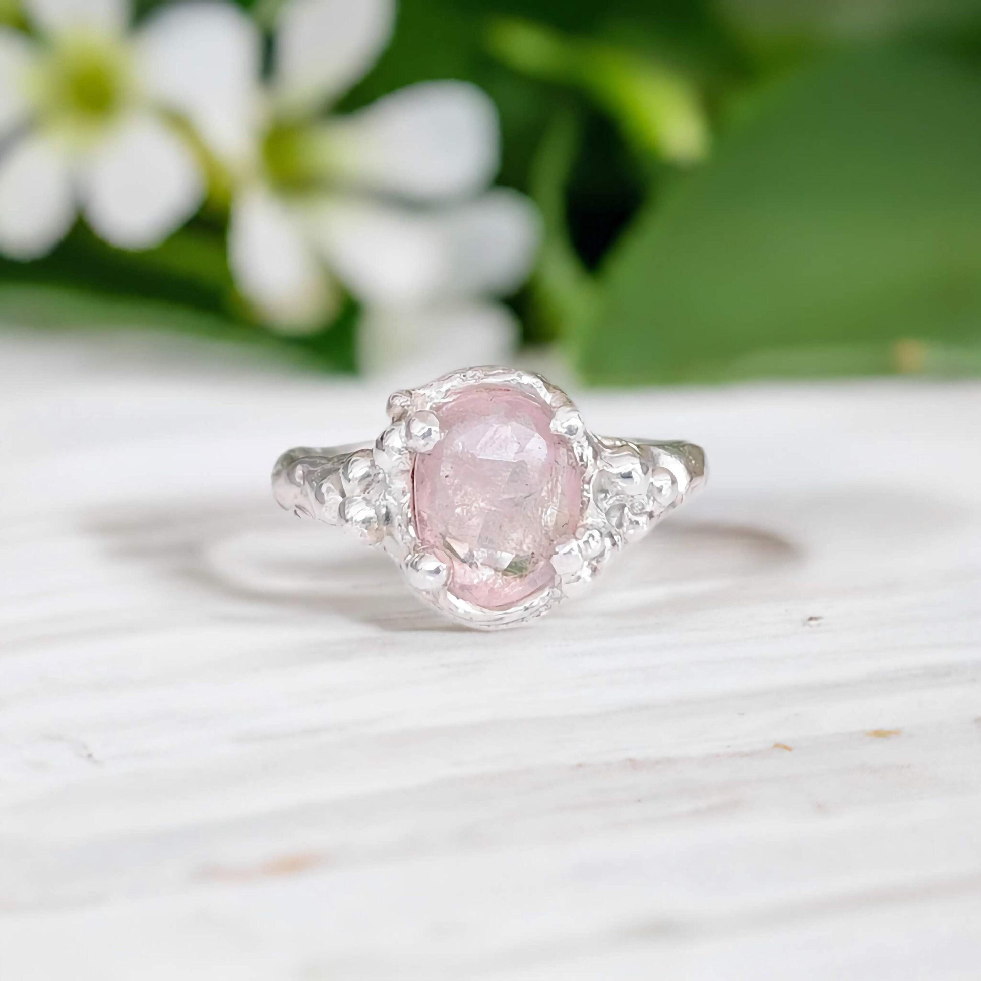 Handcrafted pink Morganite ring set in silver with floral background, showcasing elegance and charm.
