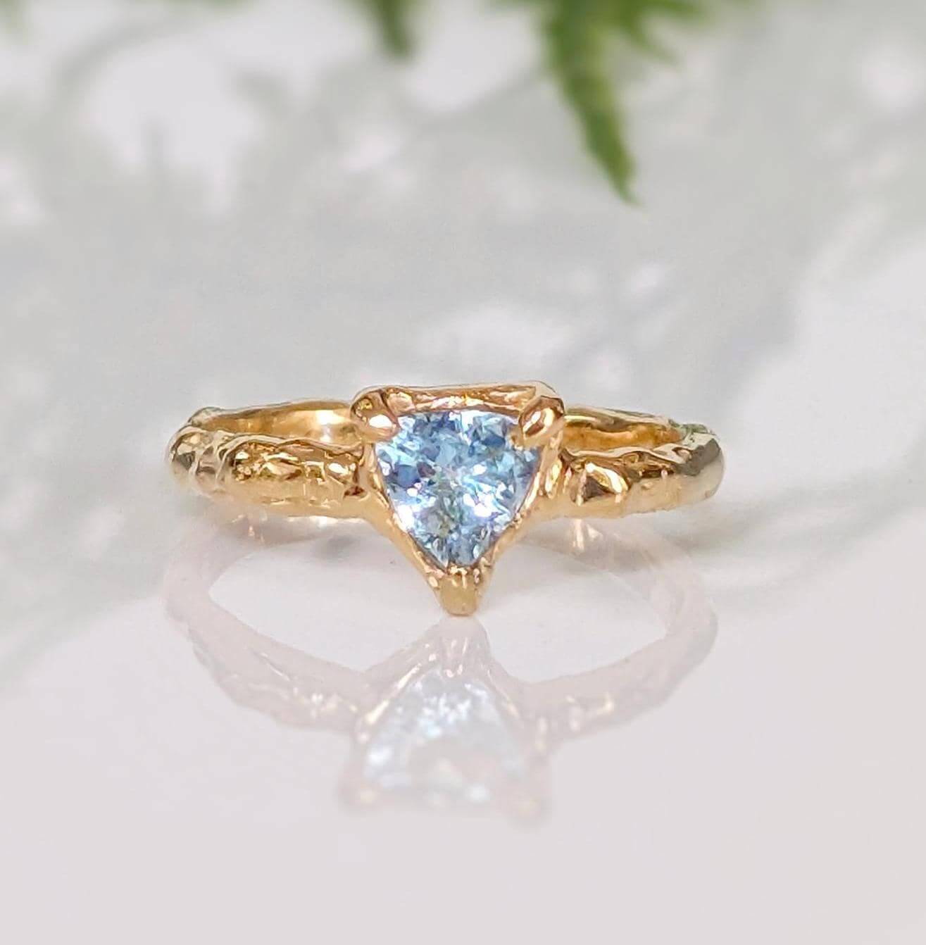 Solid Gold Aquamarine ring with textured band, featuring a unique triangular blue crystal centerpiece.
