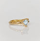 Handcrafted solid gold aquamarine ring with organic textured band, featuring a tri-shaped blue crystal.