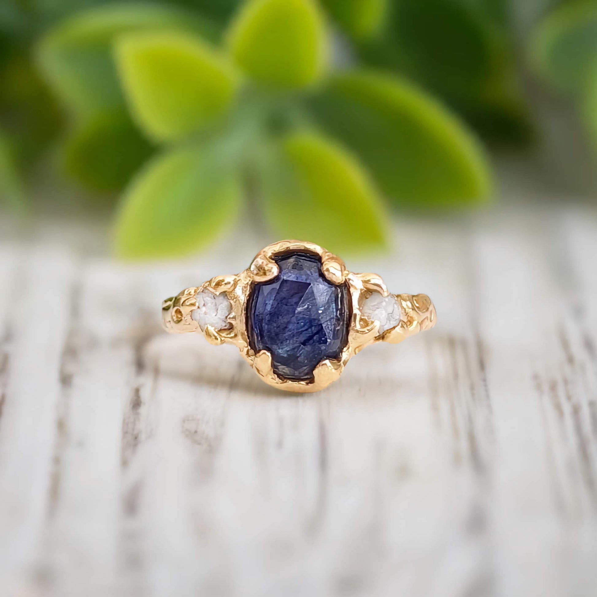 Oval Blue Sapphire and 2 small raw diamonds set by prongs on a textured Molten Solid 14k Gold band