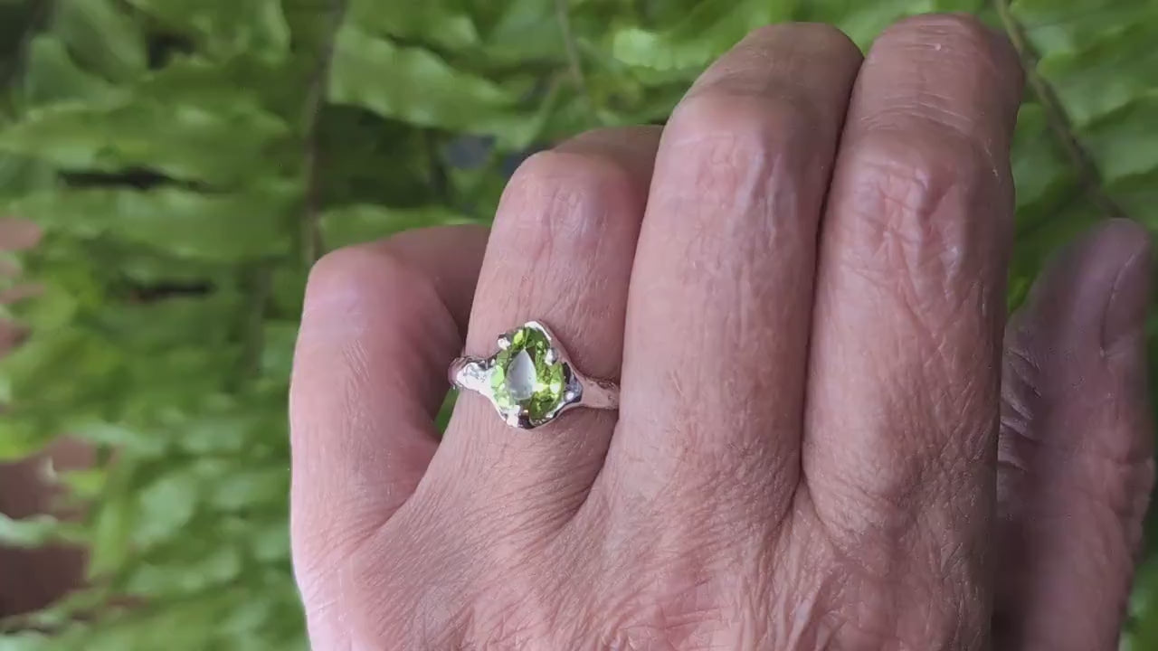 Woman's hand wear a Pear shape Peridot set on a Molten Silver textured band