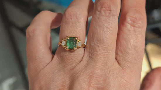 Woman's hand wearing a Raw mint green Emerald and diamonds set on Molten Gold prong setting