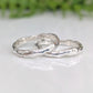 Two handcrafted Molten Silver wedding bands showcasing unique organic texture and elegance on a reflective surface.