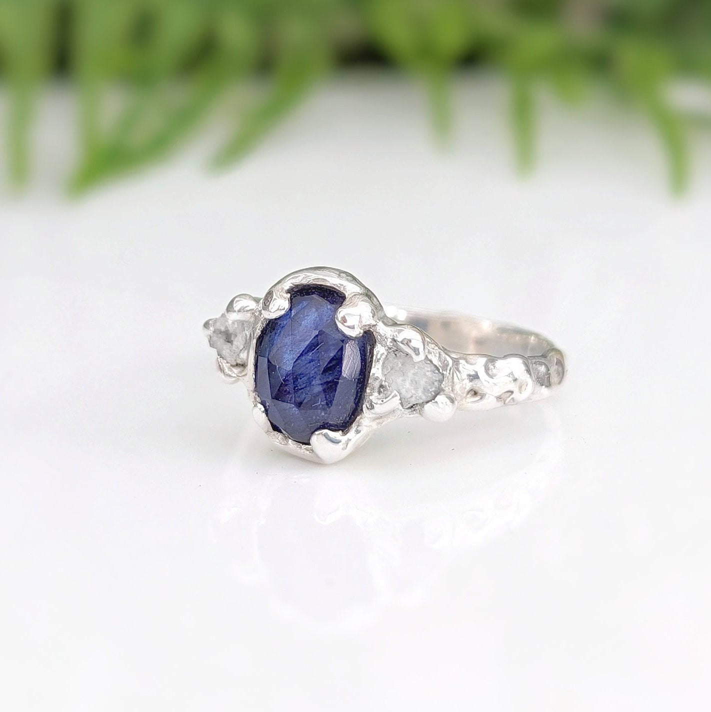 Oval Blue Sapphire and 2 small raw diamonds set by prongs on a textured Molten Solid Sterling Silver band