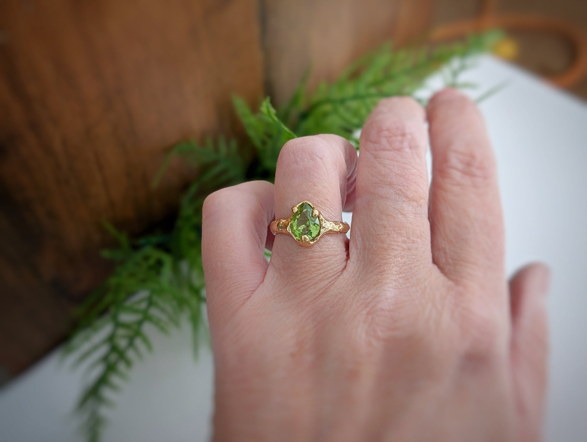 Woman's hand wearing a Large Pear shape Peridot set by prongs on a textured Molten Solid 14k Gold band