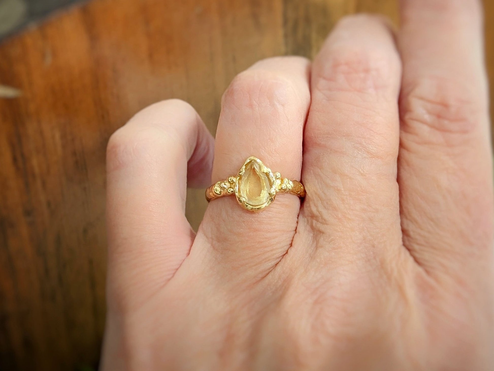 Large Pear shape Citrine set by prongs on a Solid 14k Gold Molten textured band worn on a woman's hand